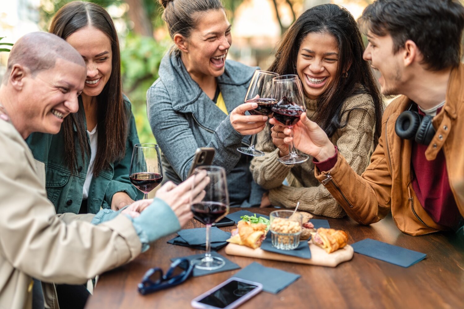 Multiracial people having fun drinking red wine out side at city winery bar